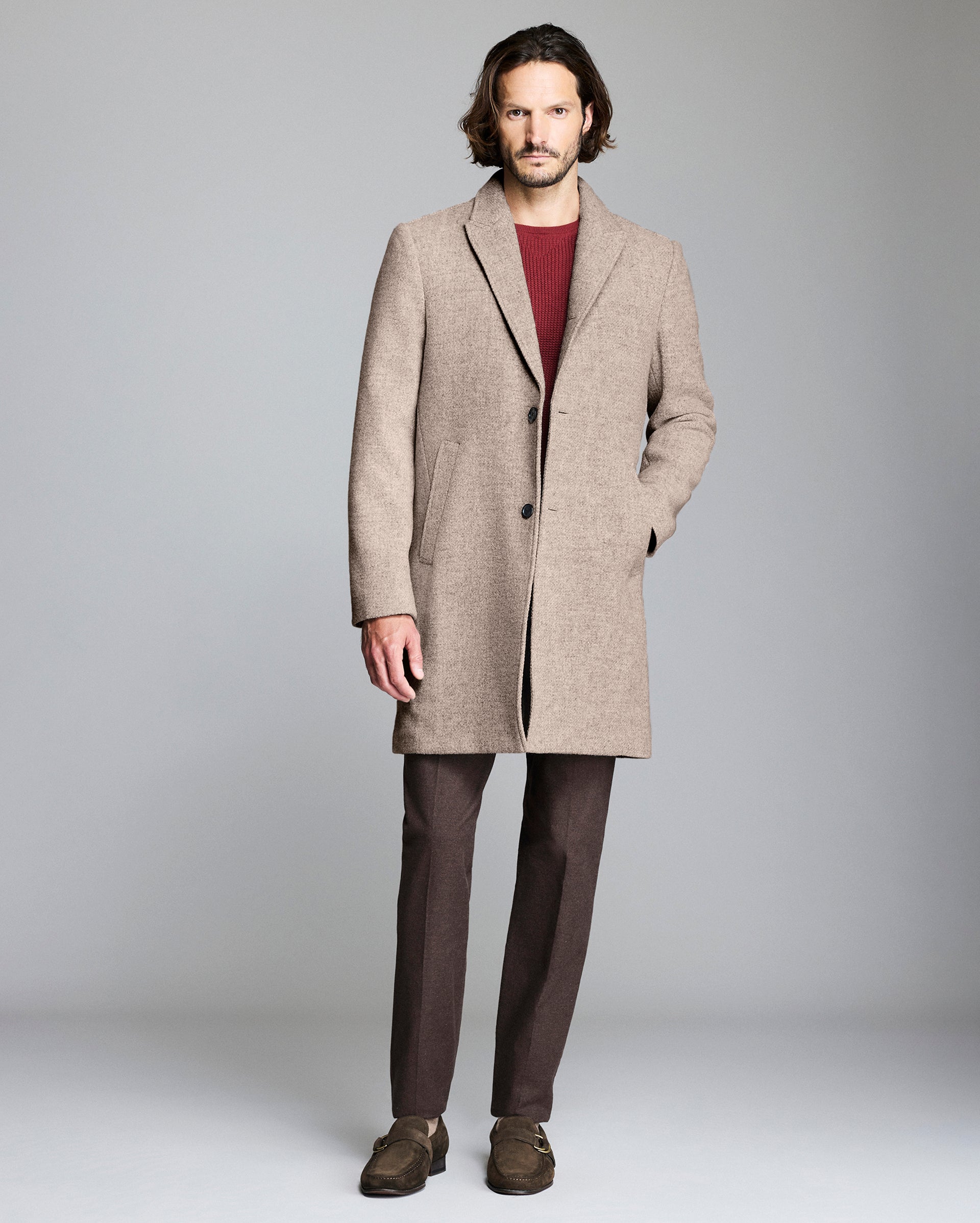 Man wearing a beige overcoat on a plain background