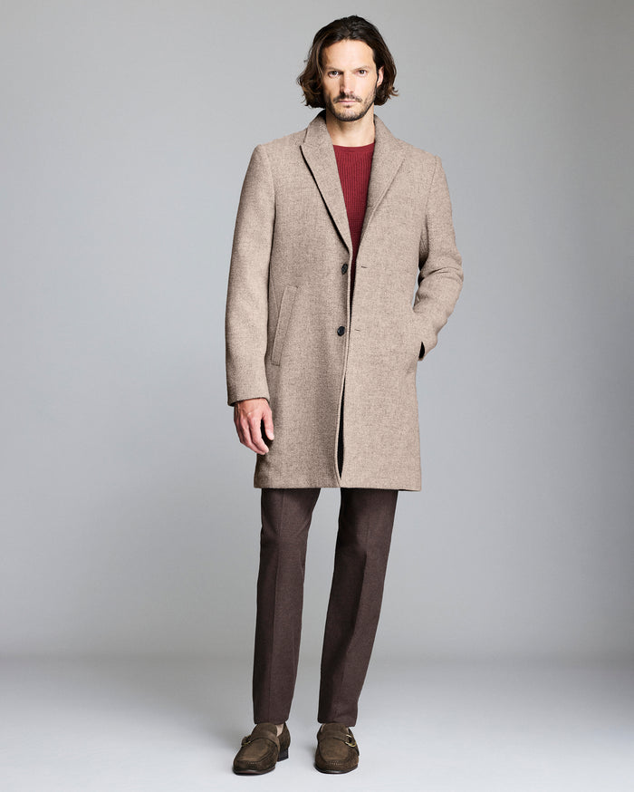 Man wearing a beige overcoat on a plain background