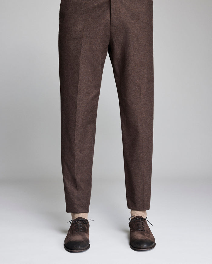 Brown pants worn with brown shoes on a light gray background