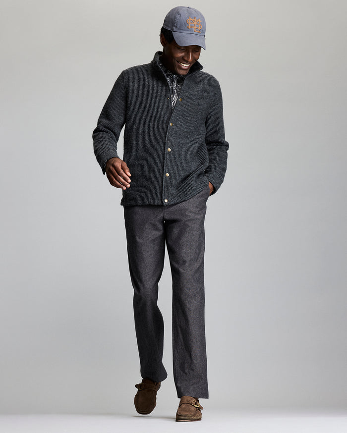 Man wearing a gray sweater, cap, and pants on a plain background