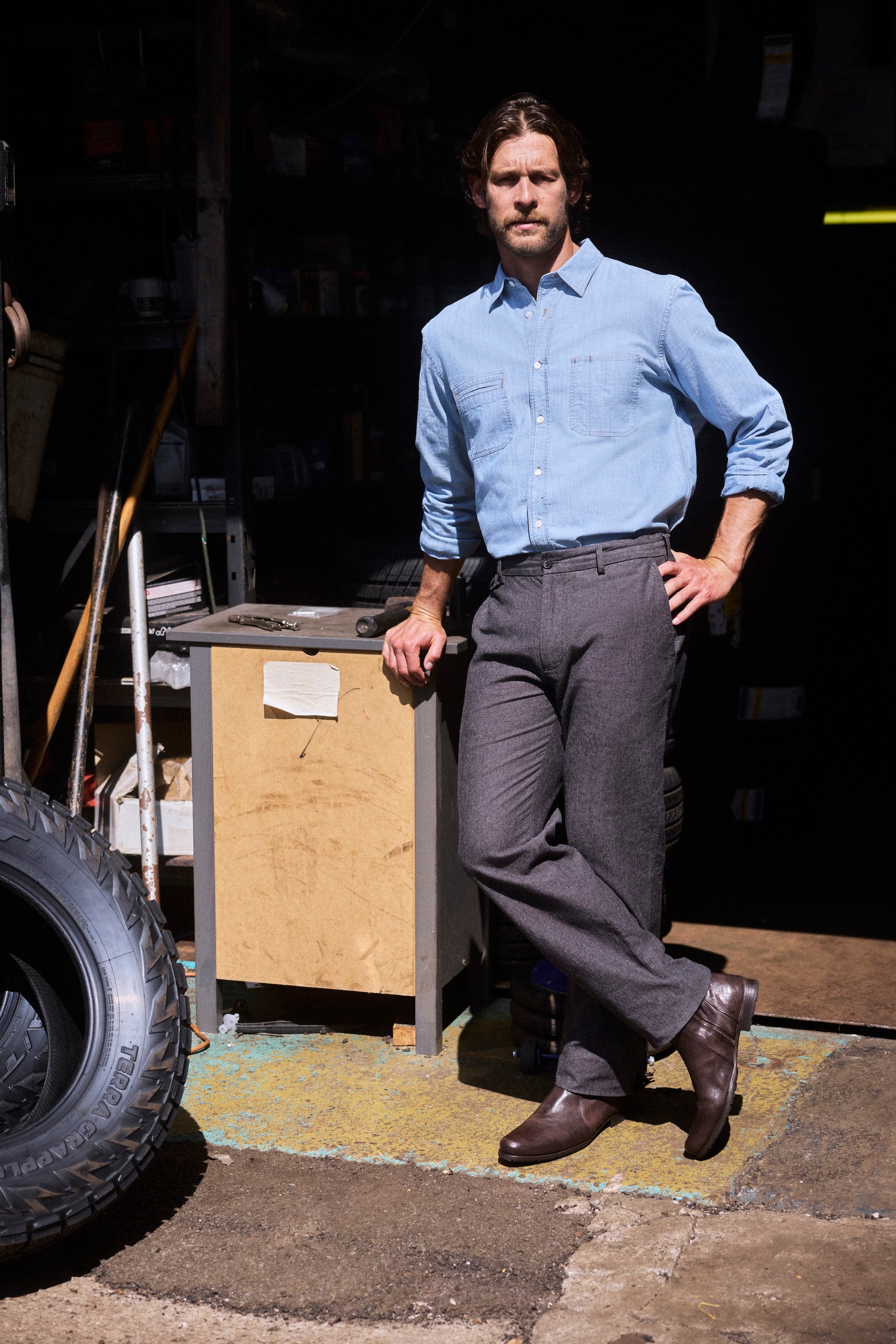 Model wears the shirt i n a garage, showing the rugged sophistication.