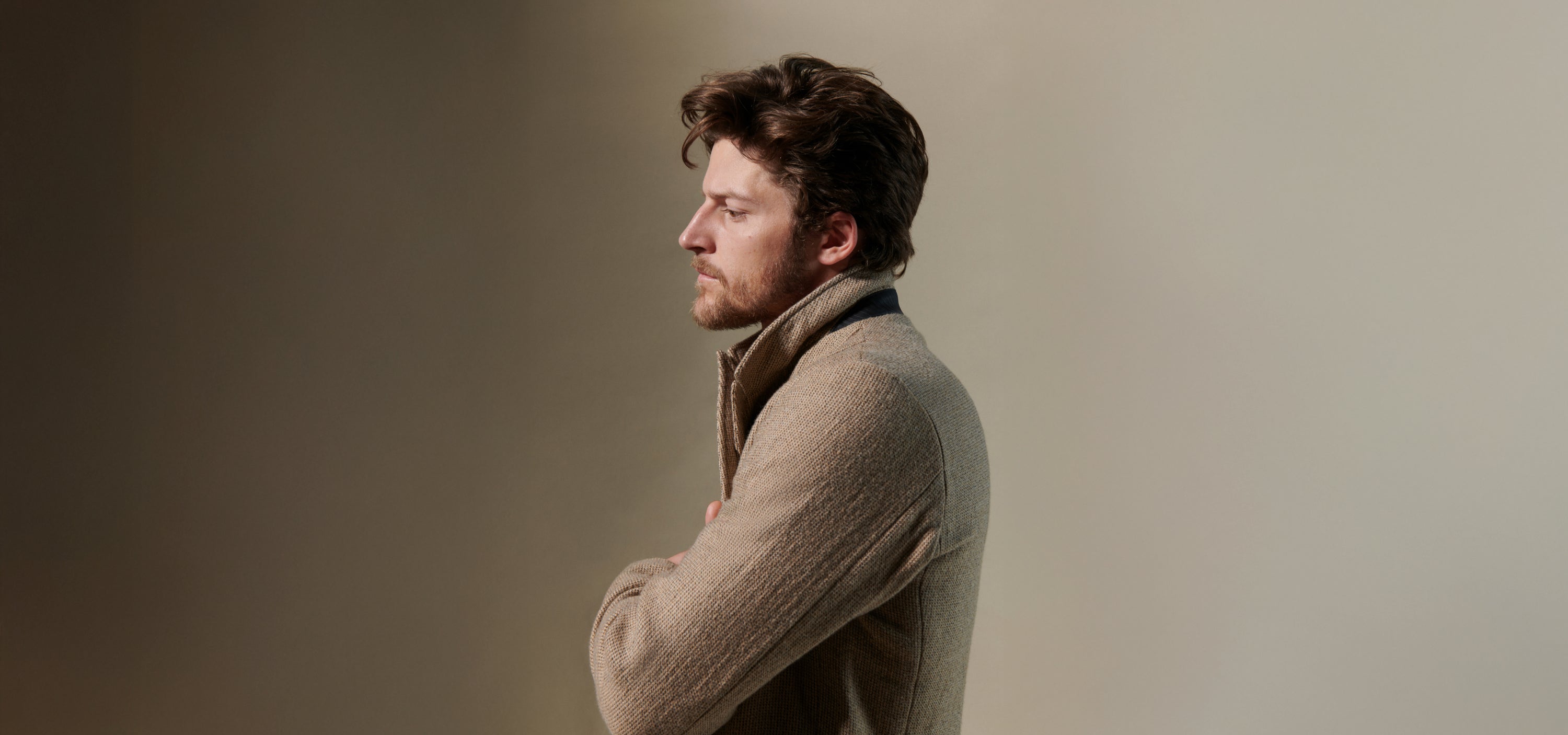 Model wears a tan suit on a beige background.