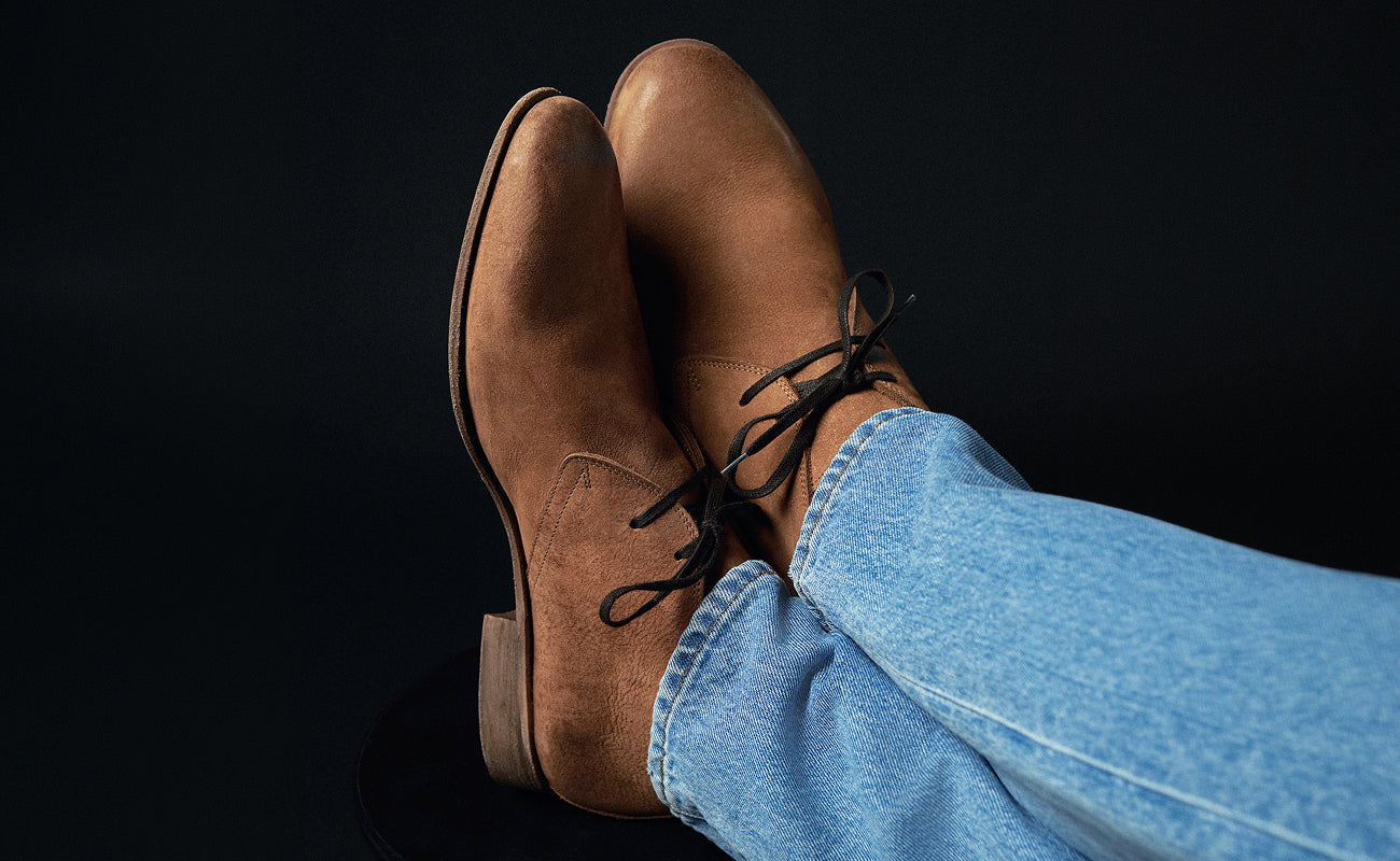 Brown leather boots and blue jeans on a black background