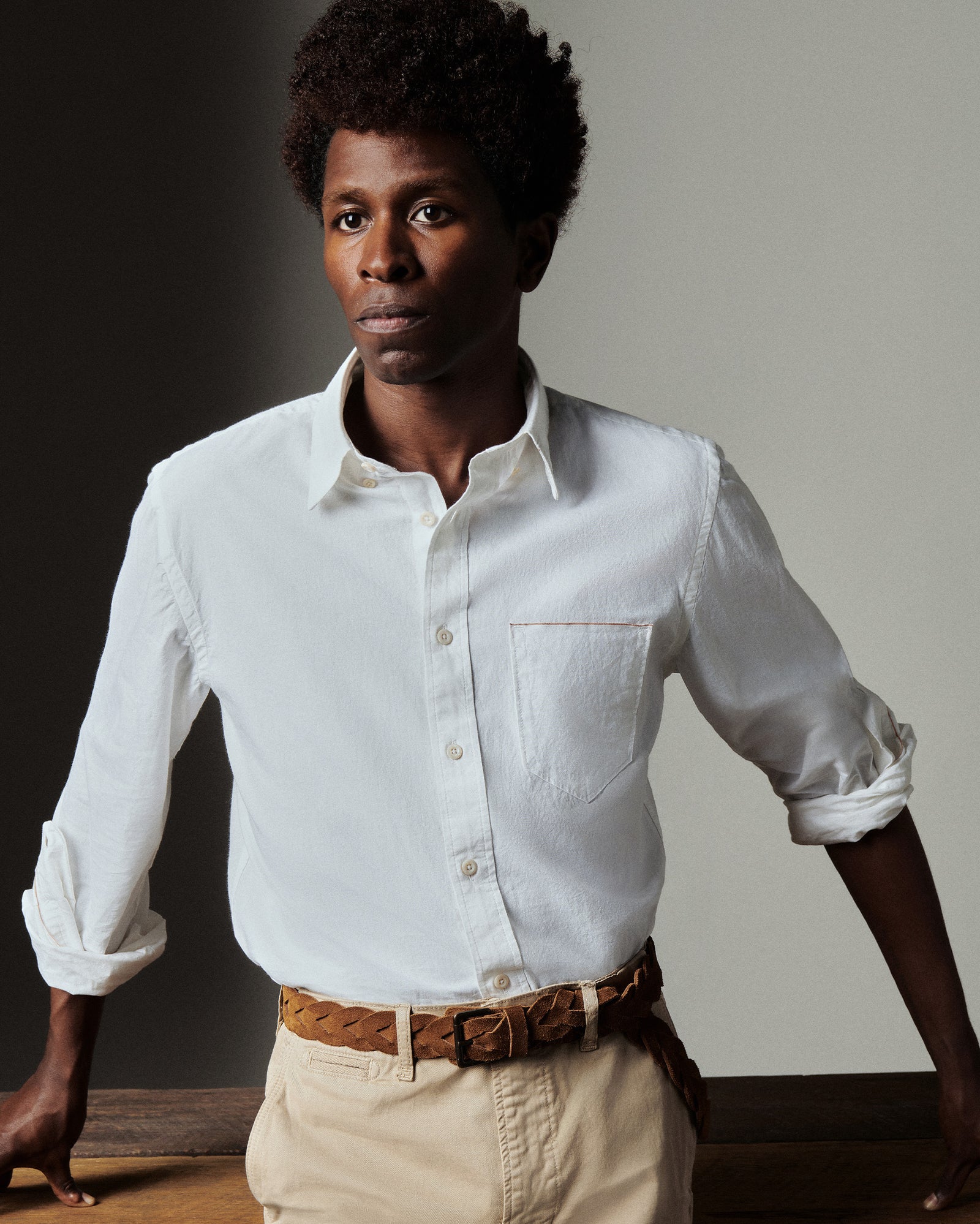 Man wearing a white shirt and beige pants against a neutral background