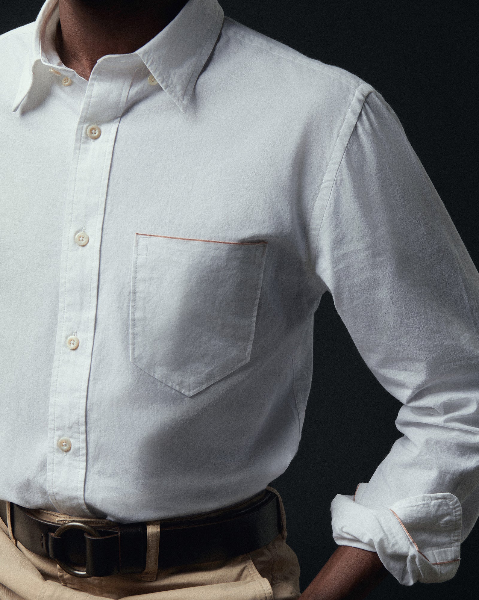 White button-up shirt with rolled-up sleeves on a black background