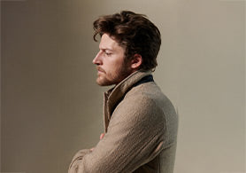 Man wearing a brown coat against a plain background