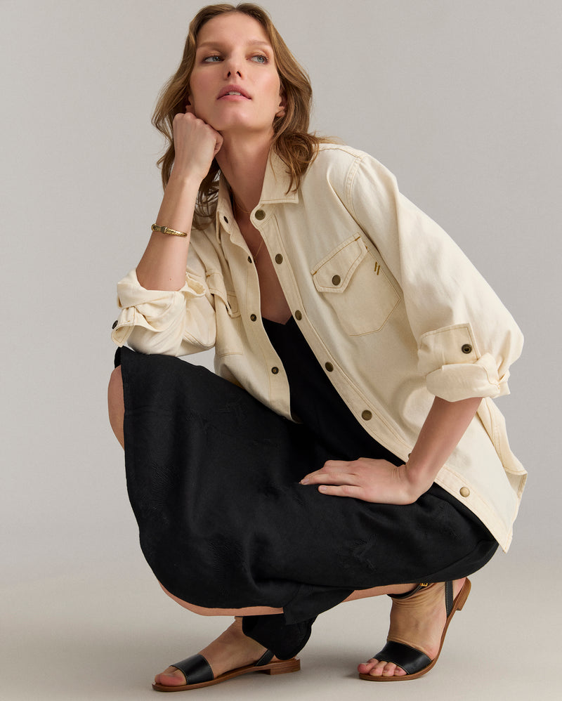Model pairs the dress with a cream overshirt.