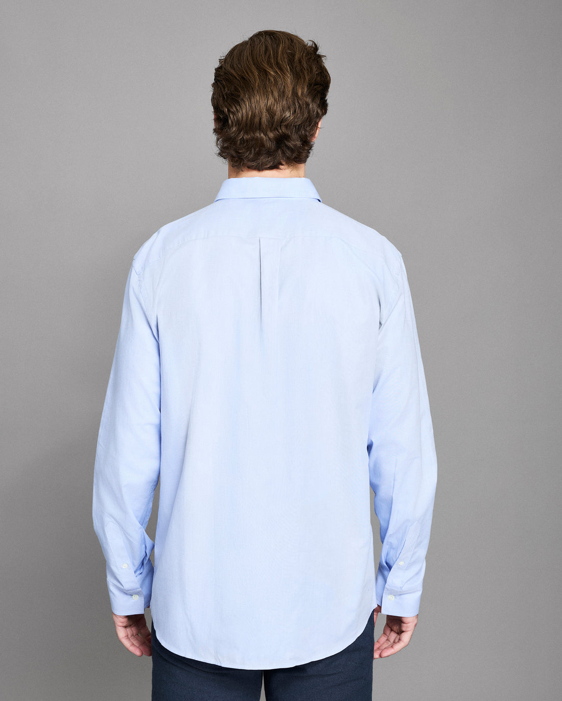Man wearing a light blue shirt against a gray background