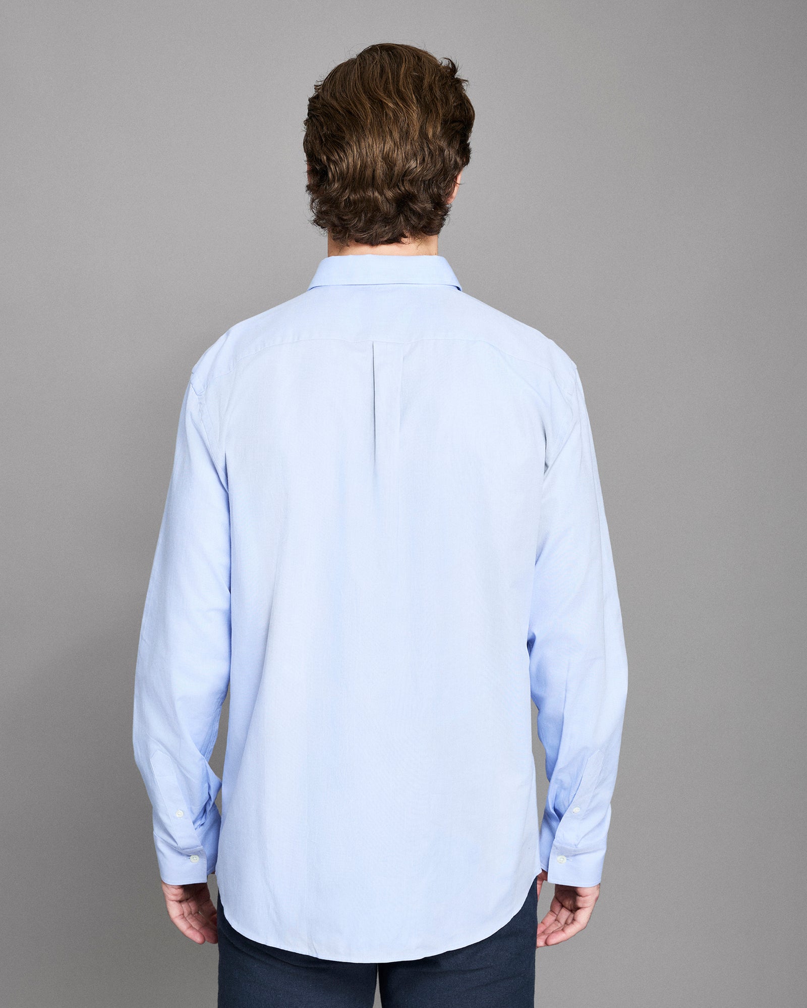 Man wearing a light blue shirt against a gray background