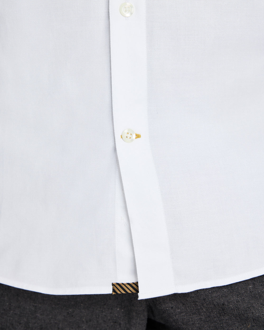 Close-up of a white shirt with a button and cuff detail on a white background