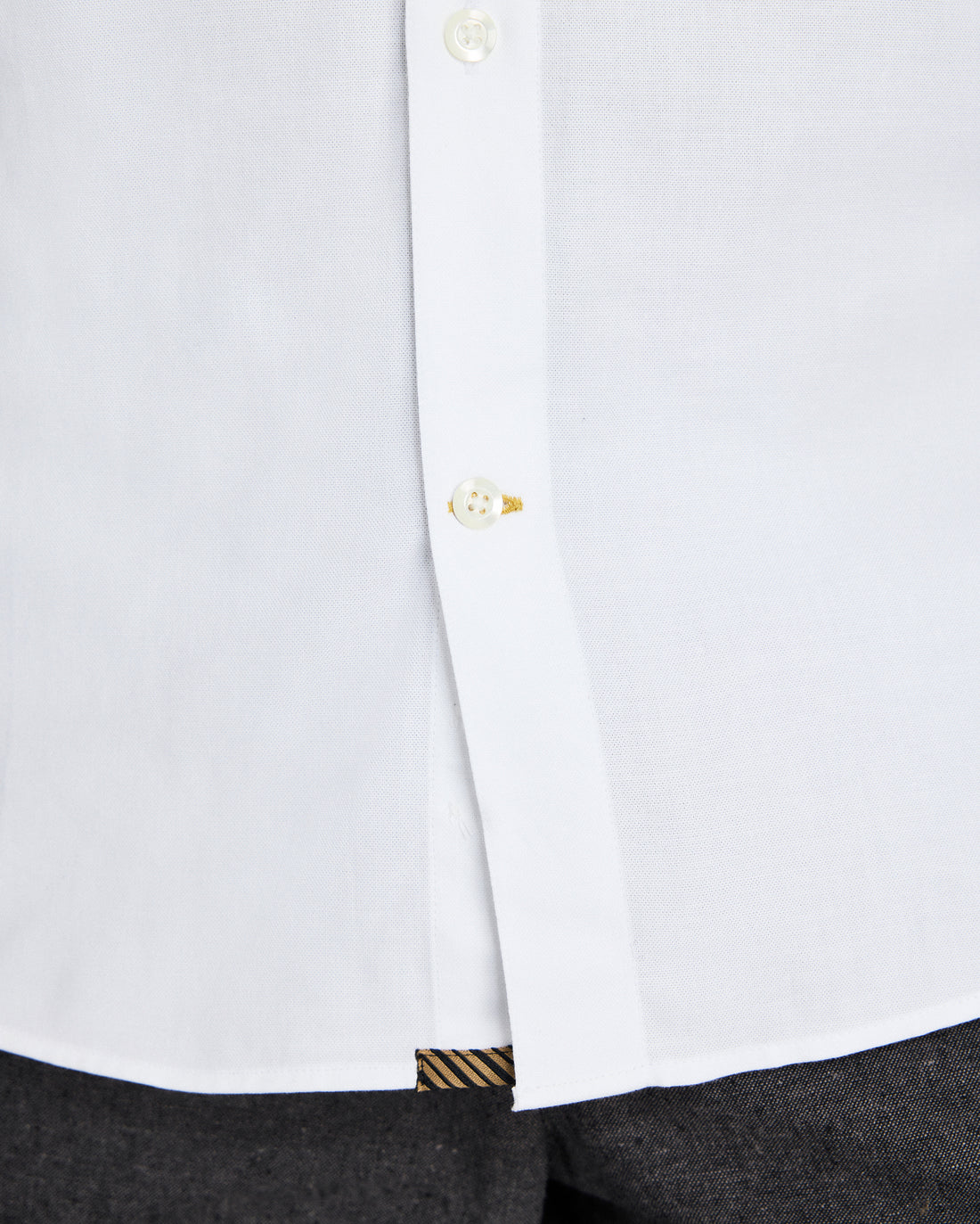 Close-up of a white shirt with a button and cuff detail on a white background