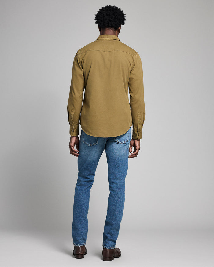 Person wearing a green shirt and blue jeans on a plain background