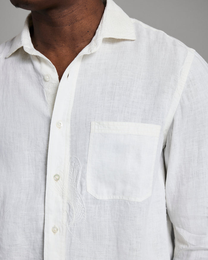 Close-up of a white linen shirt with a pocket on a gray background