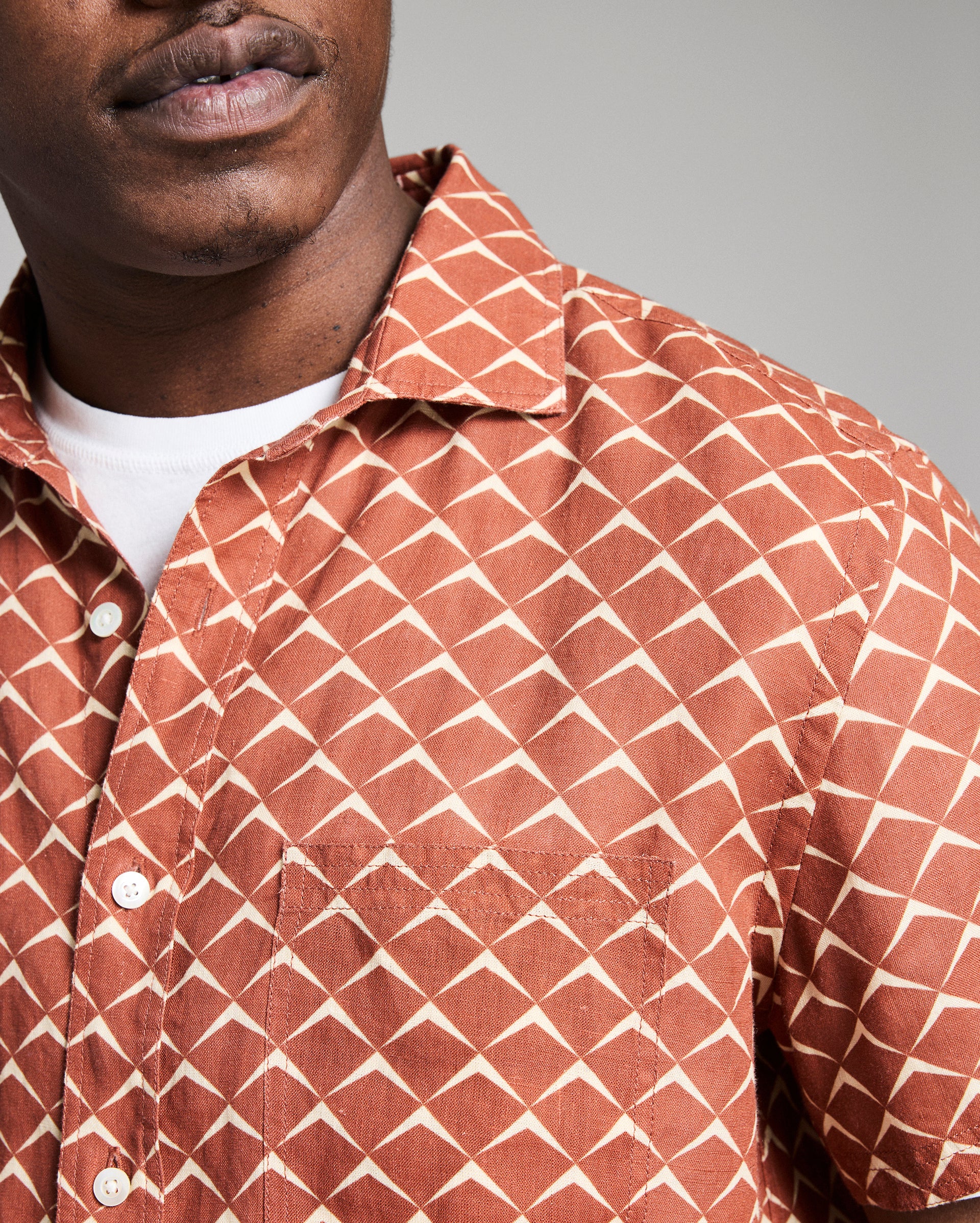 Person wearing a patterned shirt with a neutral background