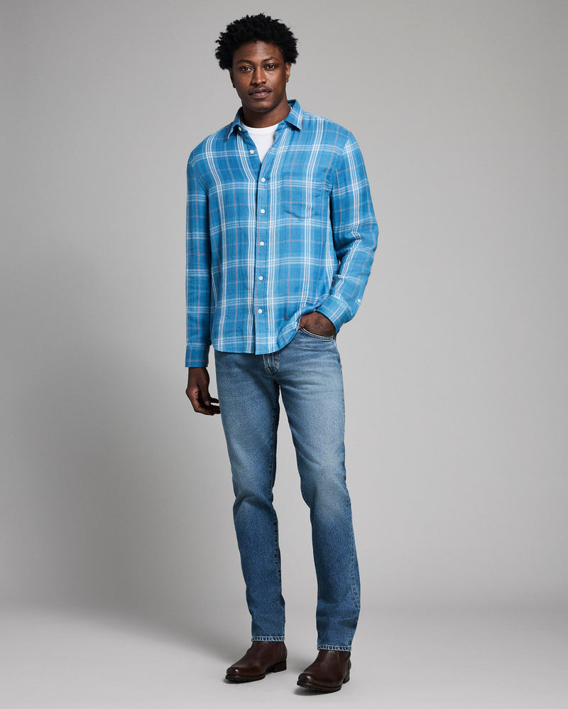 Man wearing a blue plaid shirt and jeans on a gray background Alternate