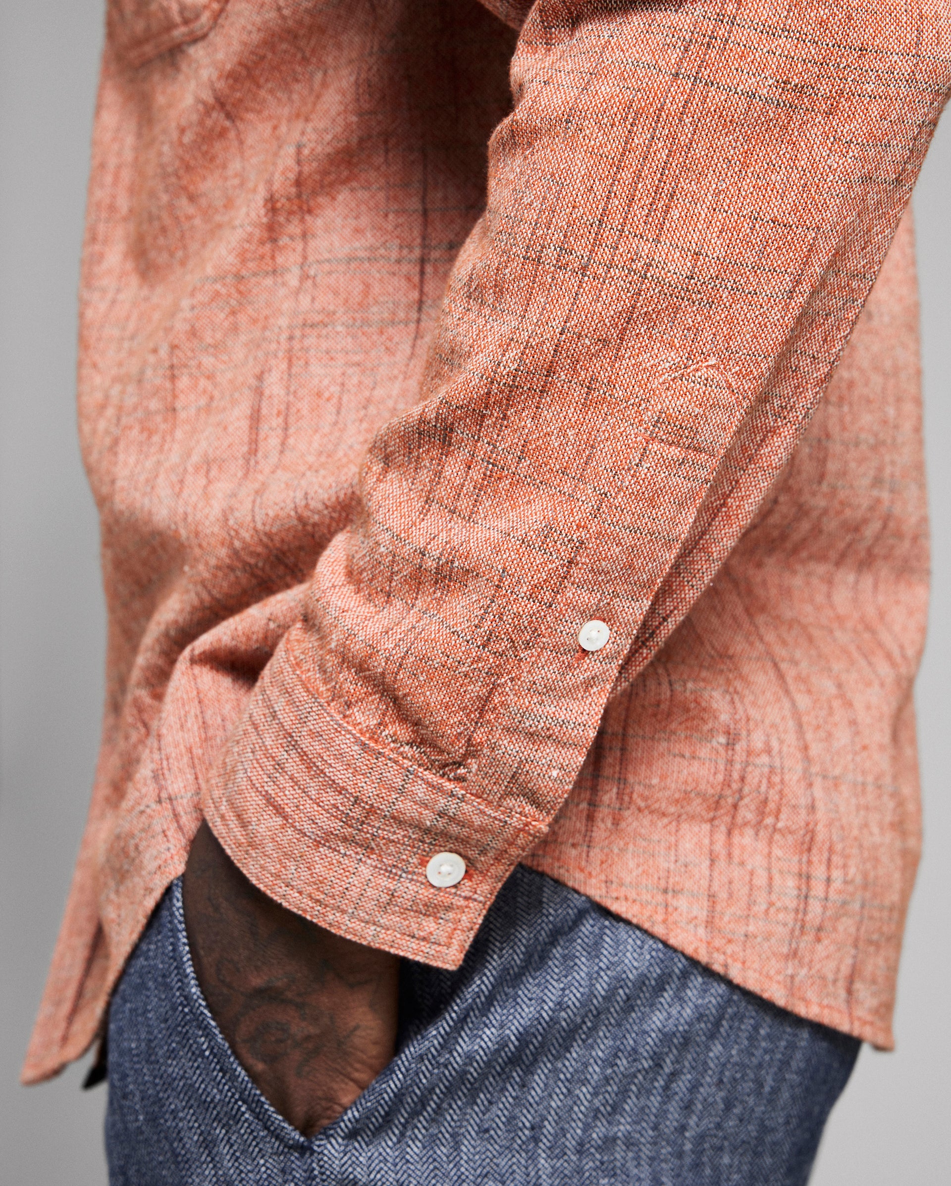 Close-up of a orange textured shirt with rolled-up sleeve on a gray background