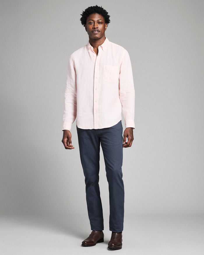 Man wearing a light pink shirt and dark blue pants on a gray background