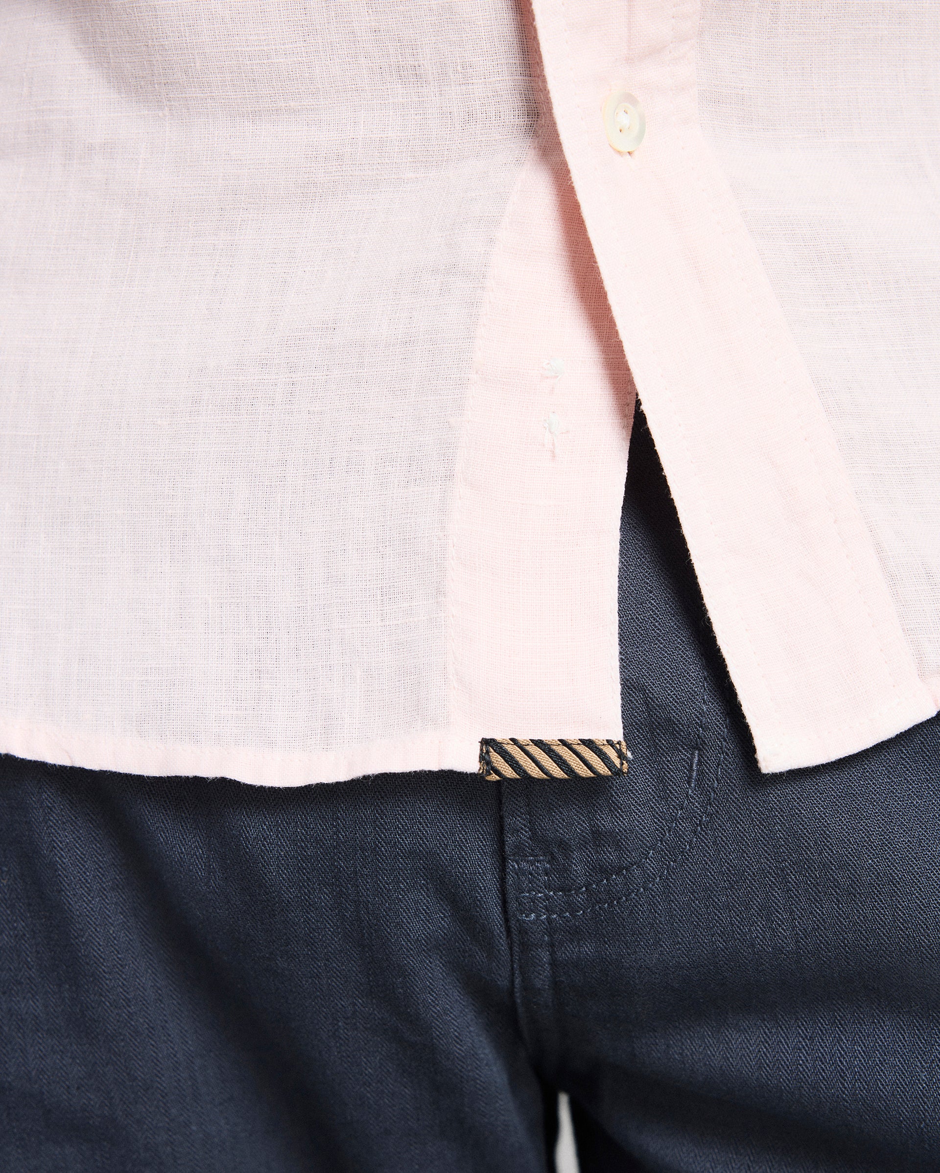Close-up of a white shirt with a collar and navy pants.