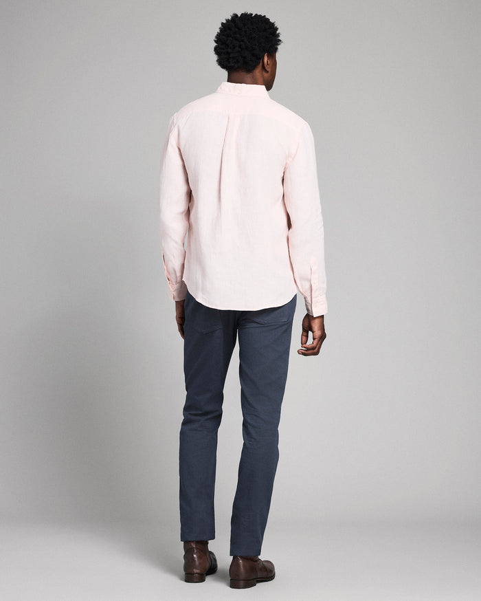 Man wearing a light pink shirt and dark blue pants on a gray background