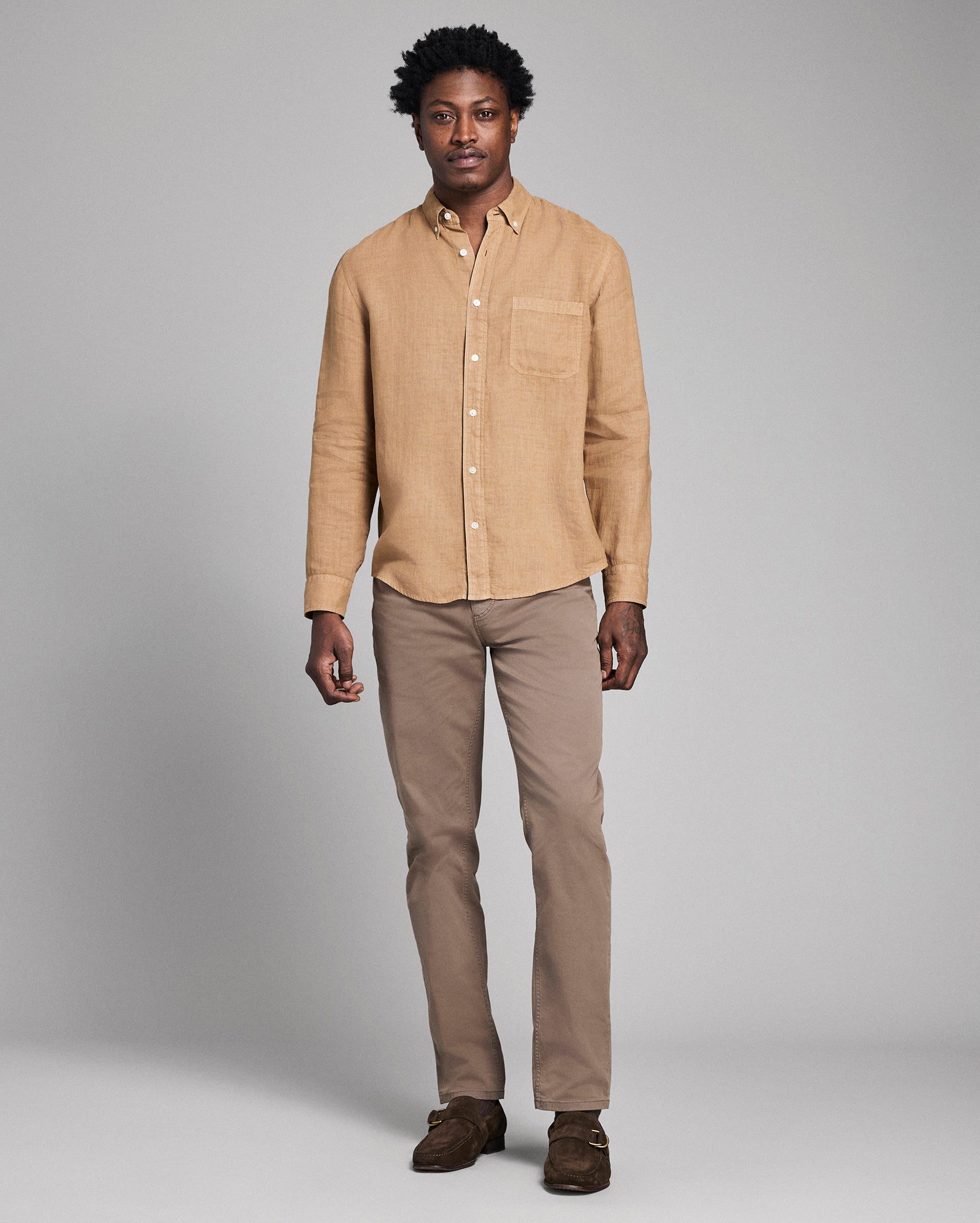 Man wearing a beige shirt and pants on a gray background