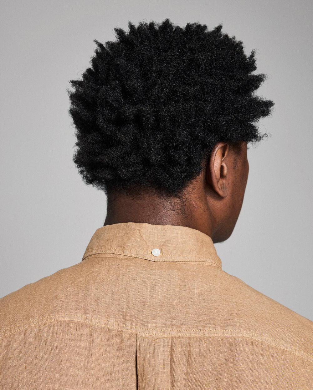 Person wearing a beige shirt with a plain background