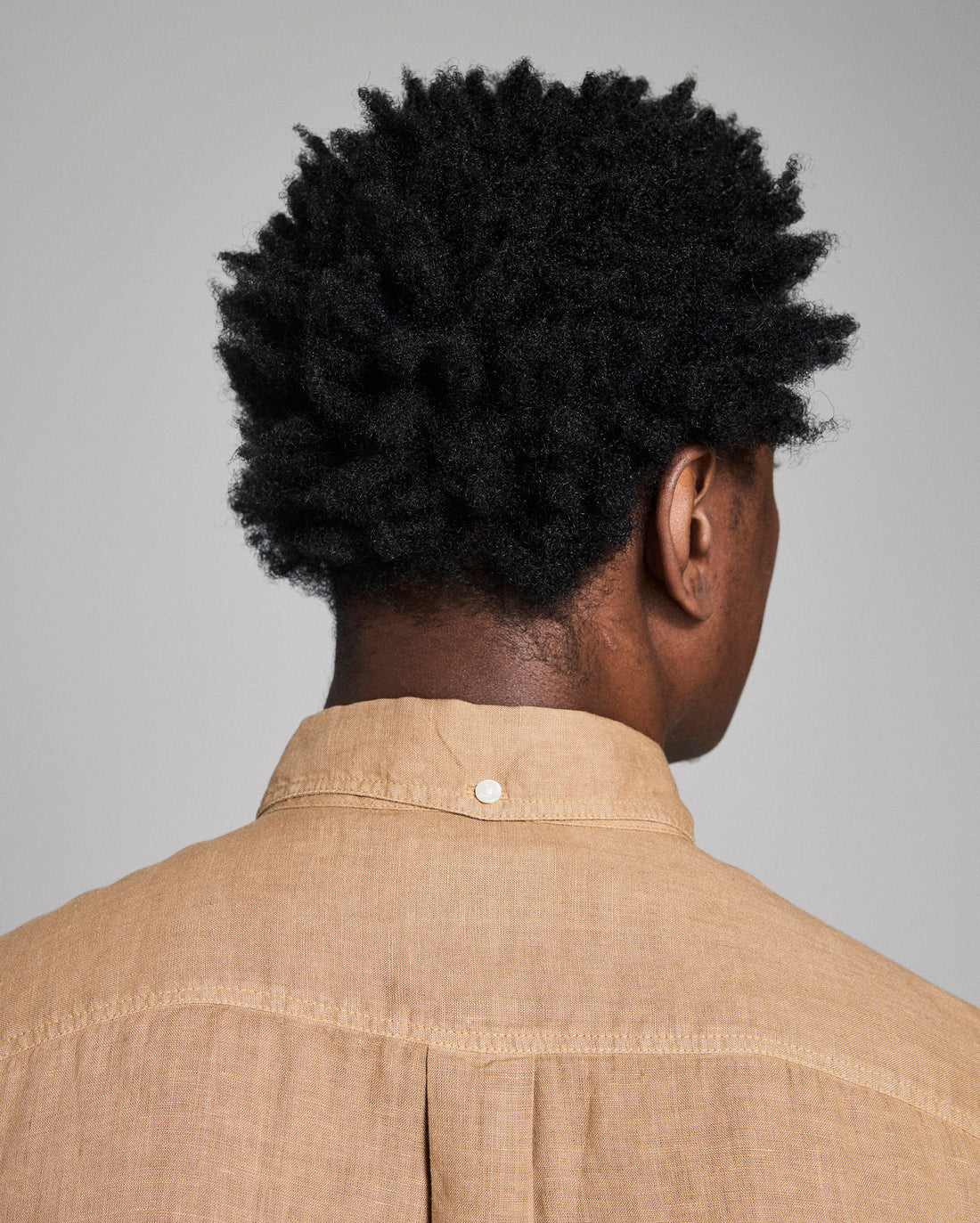 Person wearing a beige shirt with a plain background