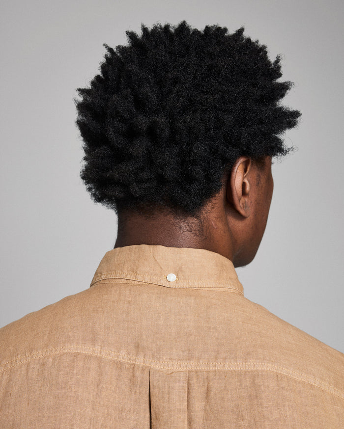 Person wearing a beige shirt with a plain background