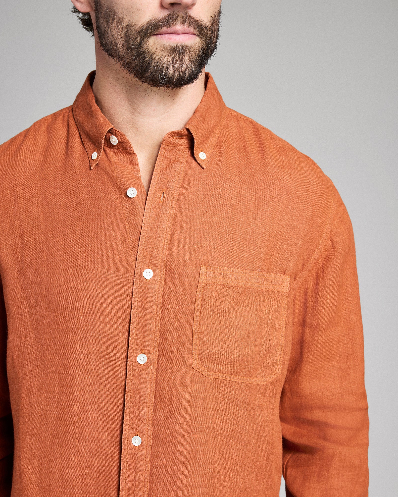 Man wearing a brown button-up shirt against a gray background