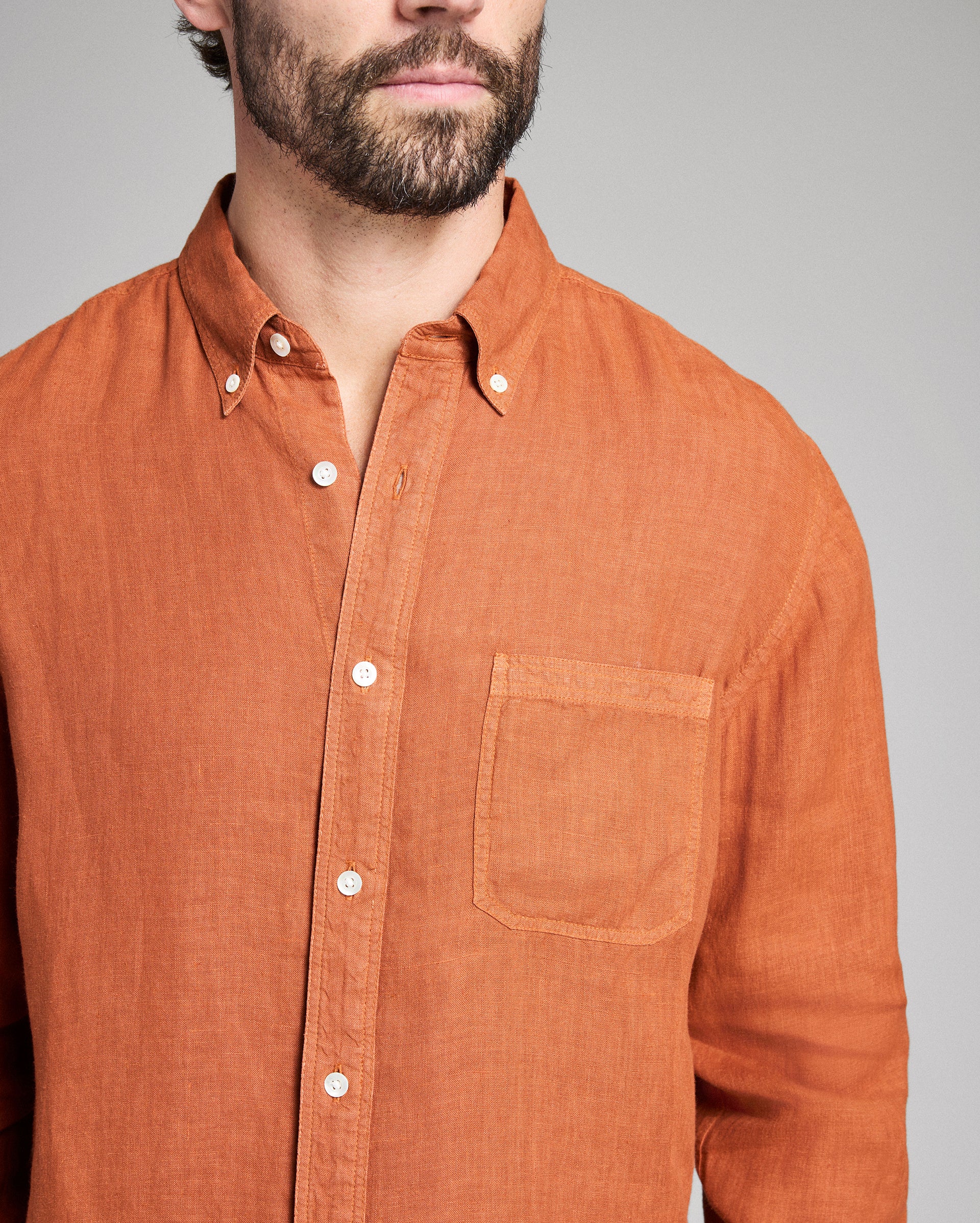 Man wearing a brown button-up shirt against a gray background