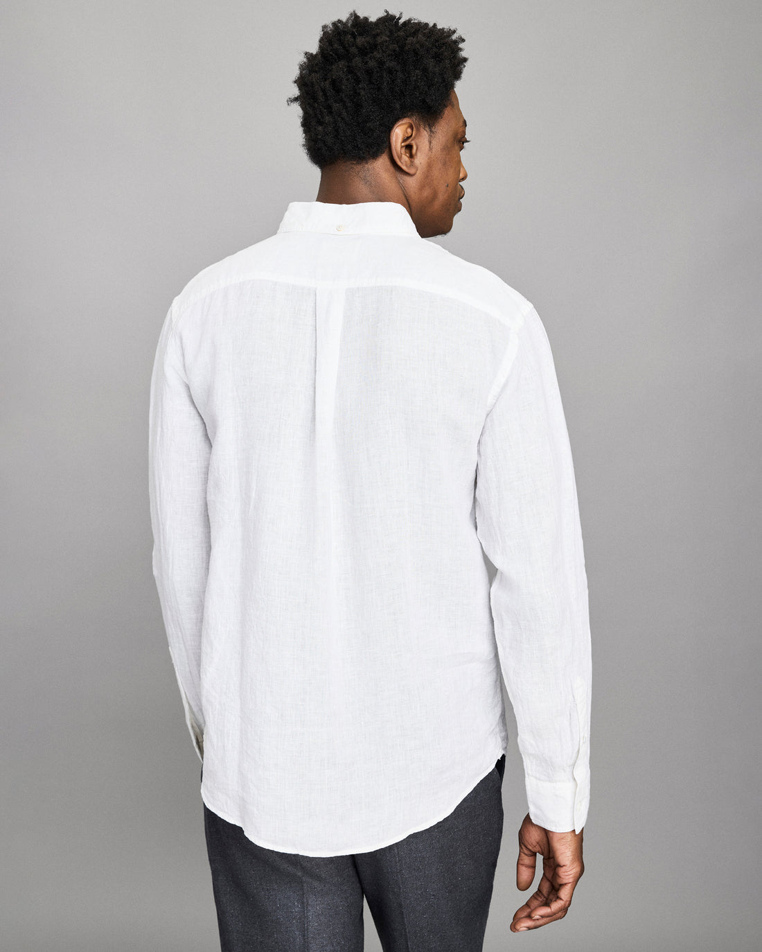 Man wearing a white button-up shirt against a gray background