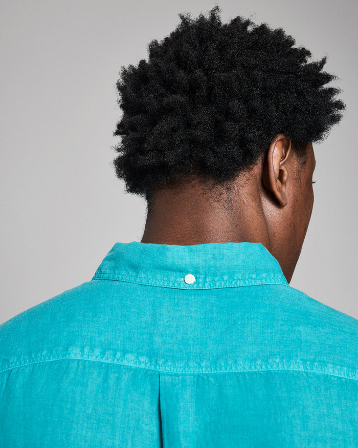 Person wearing a teal shirt with a gray background