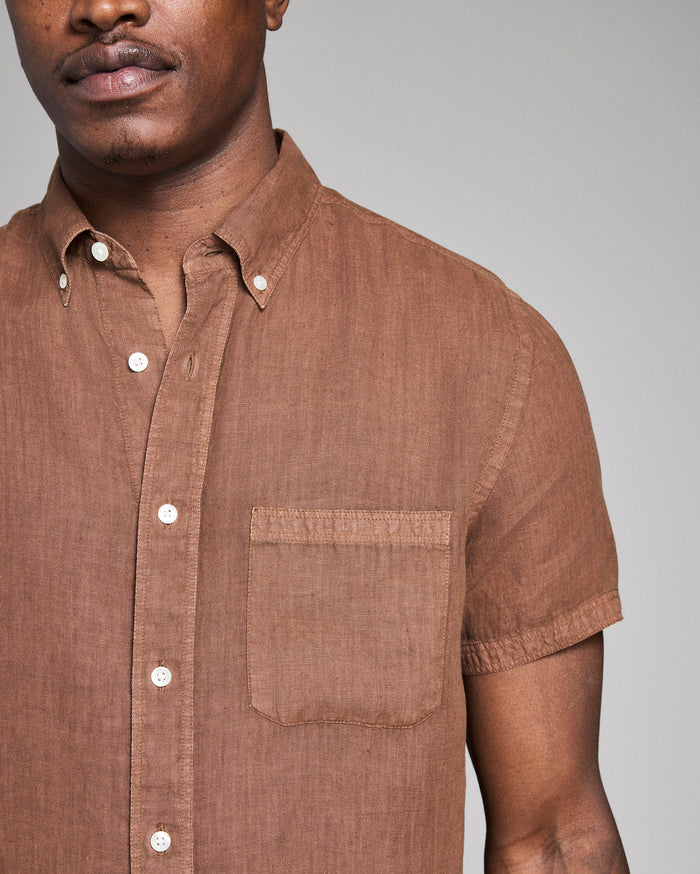 Man wearing a brown short-sleeve shirt against a gray background