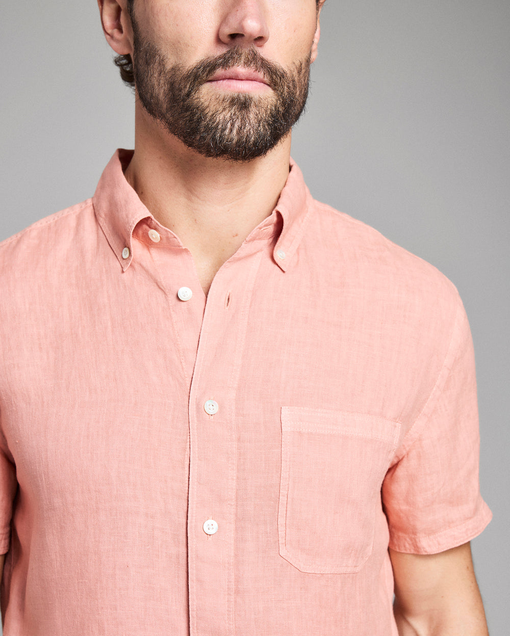 Man wearing a pink short-sleeve shirt against a gray background