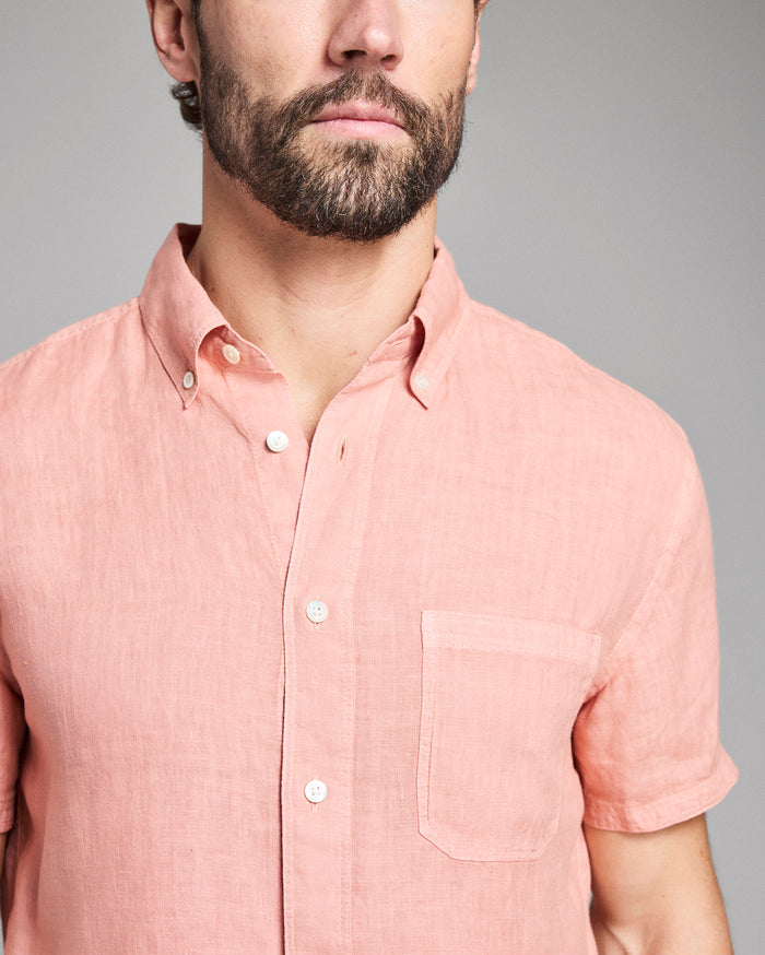 Man wearing a pink short-sleeve shirt against a gray background