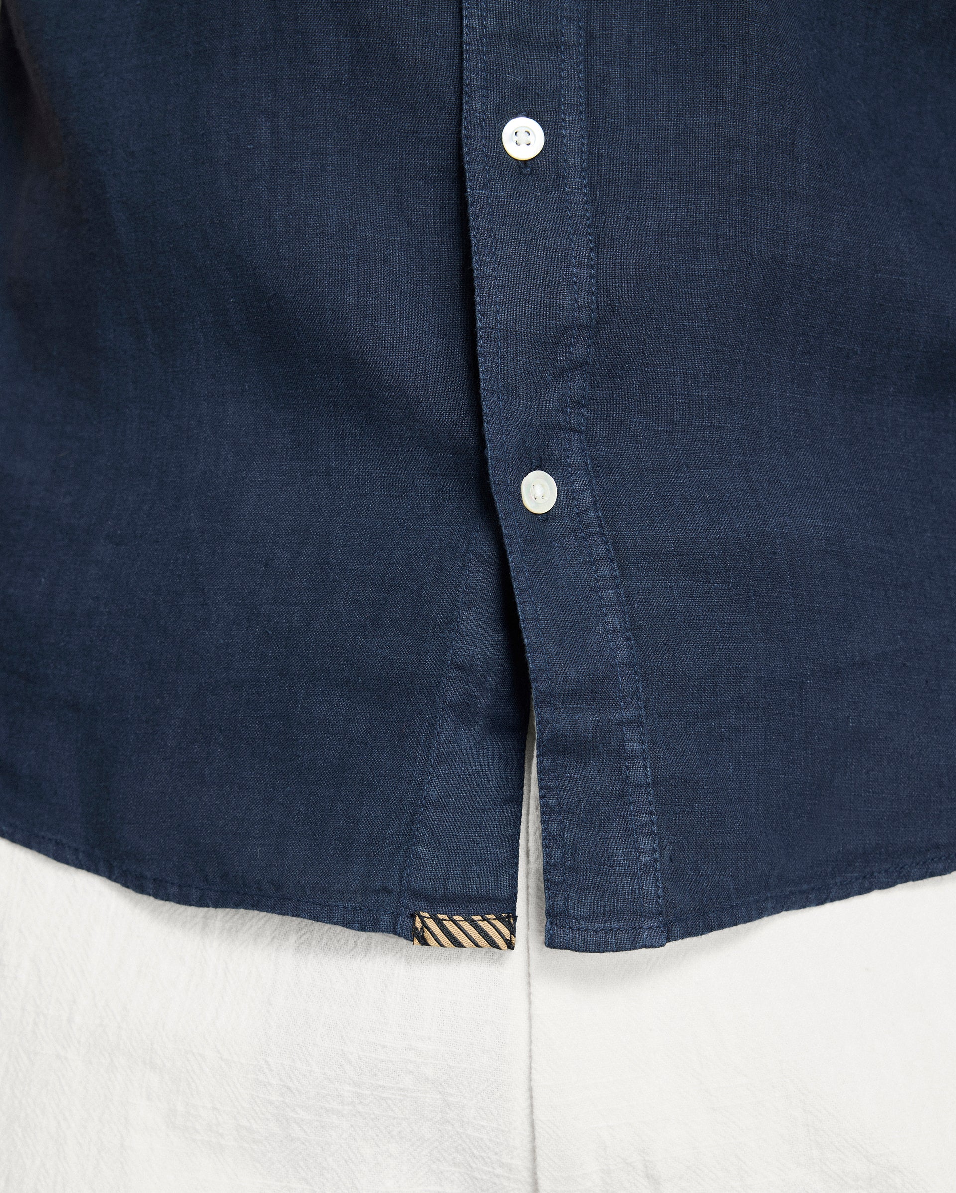 Close-up of a navy blue shirt collar with buttons on a white background
