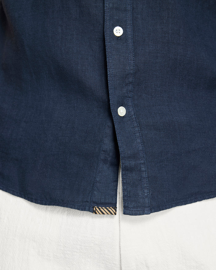 Close-up of a navy blue shirt collar with buttons on a white background