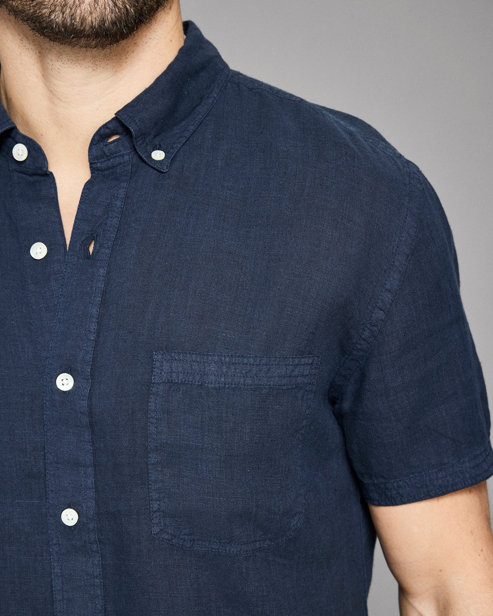 Navy blue short-sleeve shirt worn by a person on a gray background