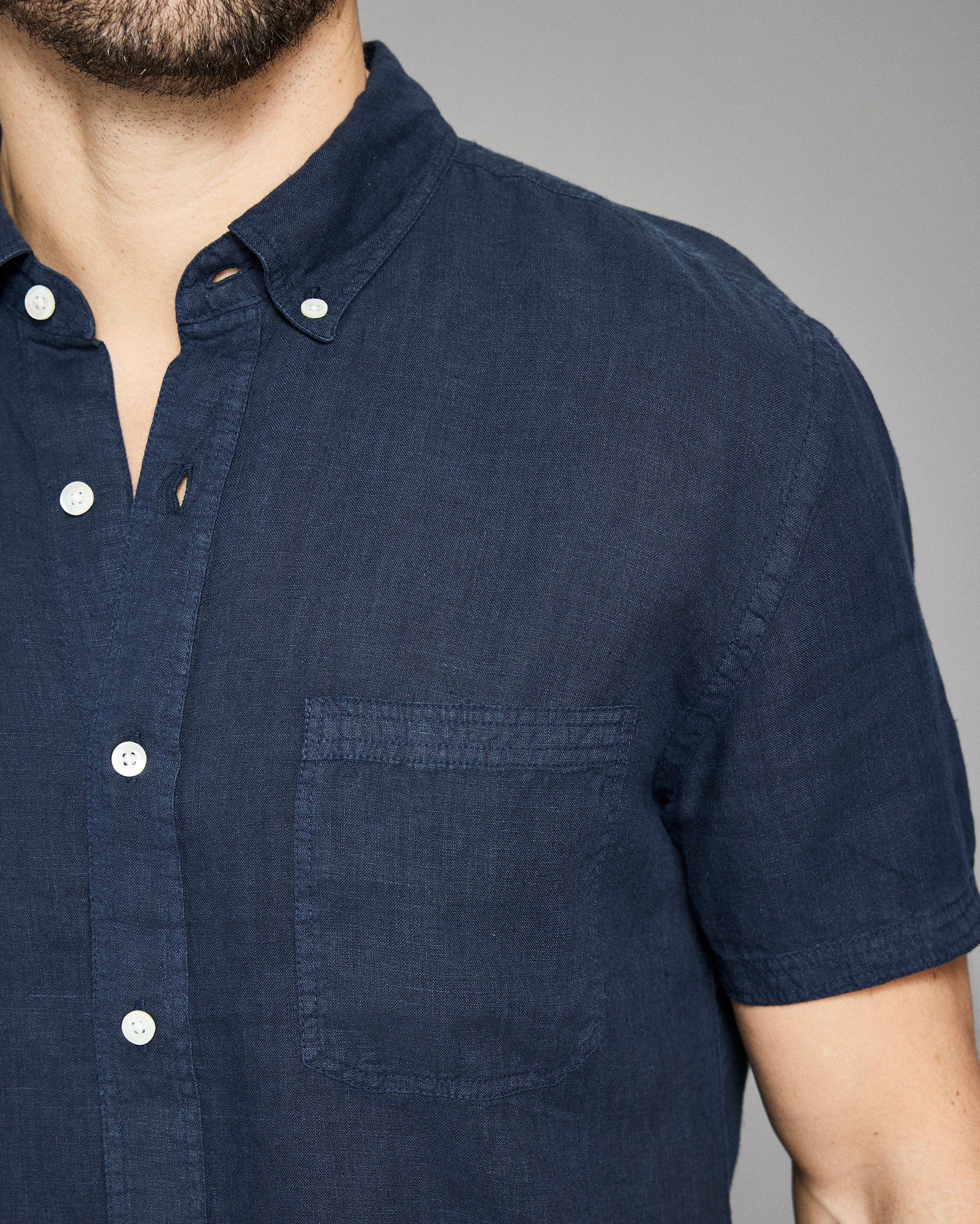 Navy blue short-sleeve shirt worn by a person on a gray background