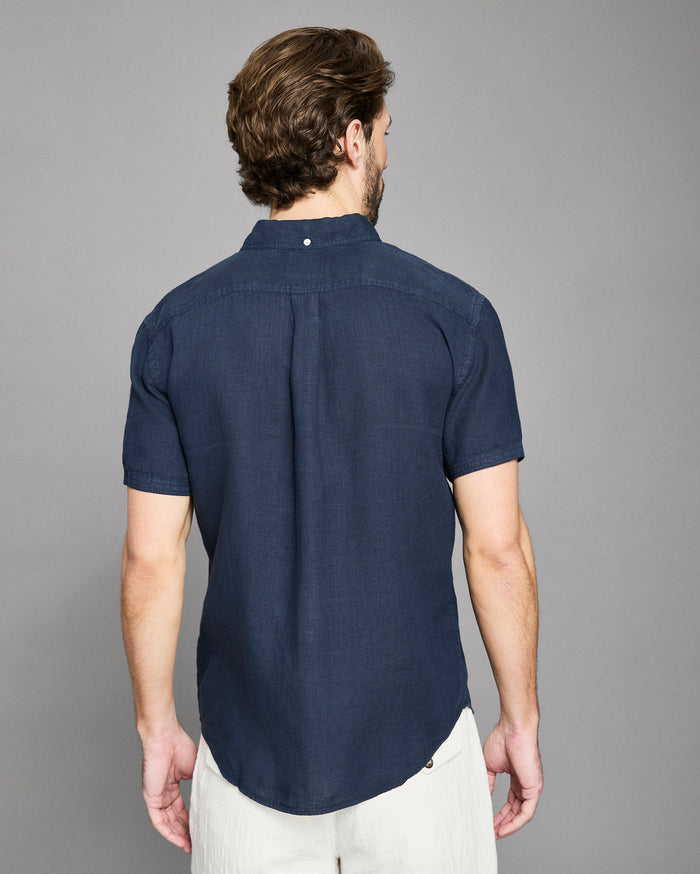 Man wearing a navy blue short-sleeve shirt against a gray background