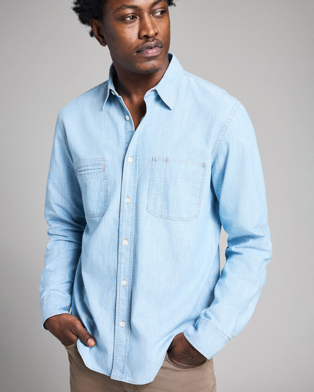 Man wearing a light blue denim shirt against a plain background