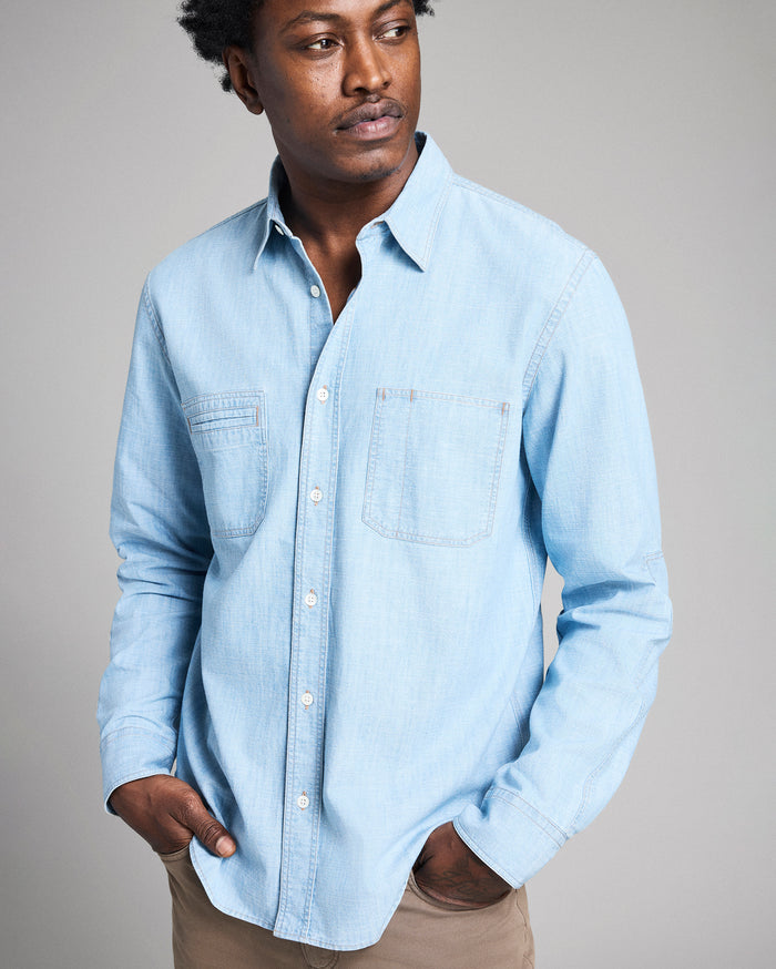 Man wearing a light blue denim shirt against a plain background