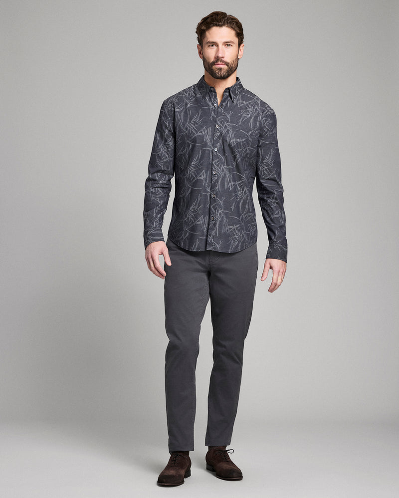 Man wearing a patterned dark shirt and gray pants on a gray background Alternate