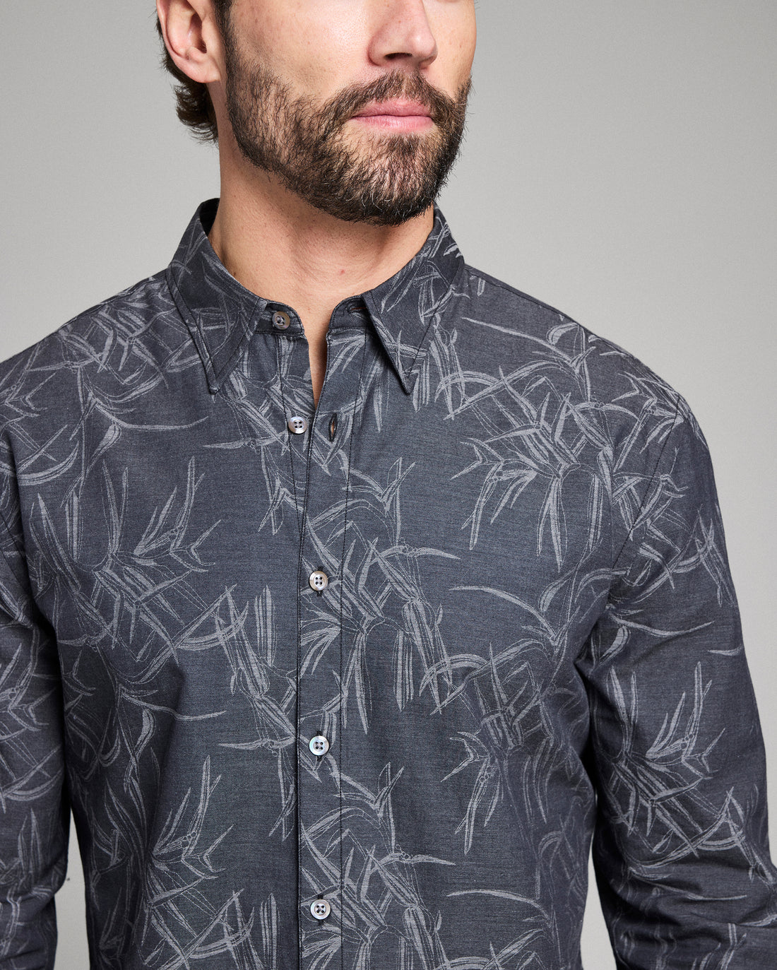 Man wearing a dark gray shirt with a subtle pattern on a plain background