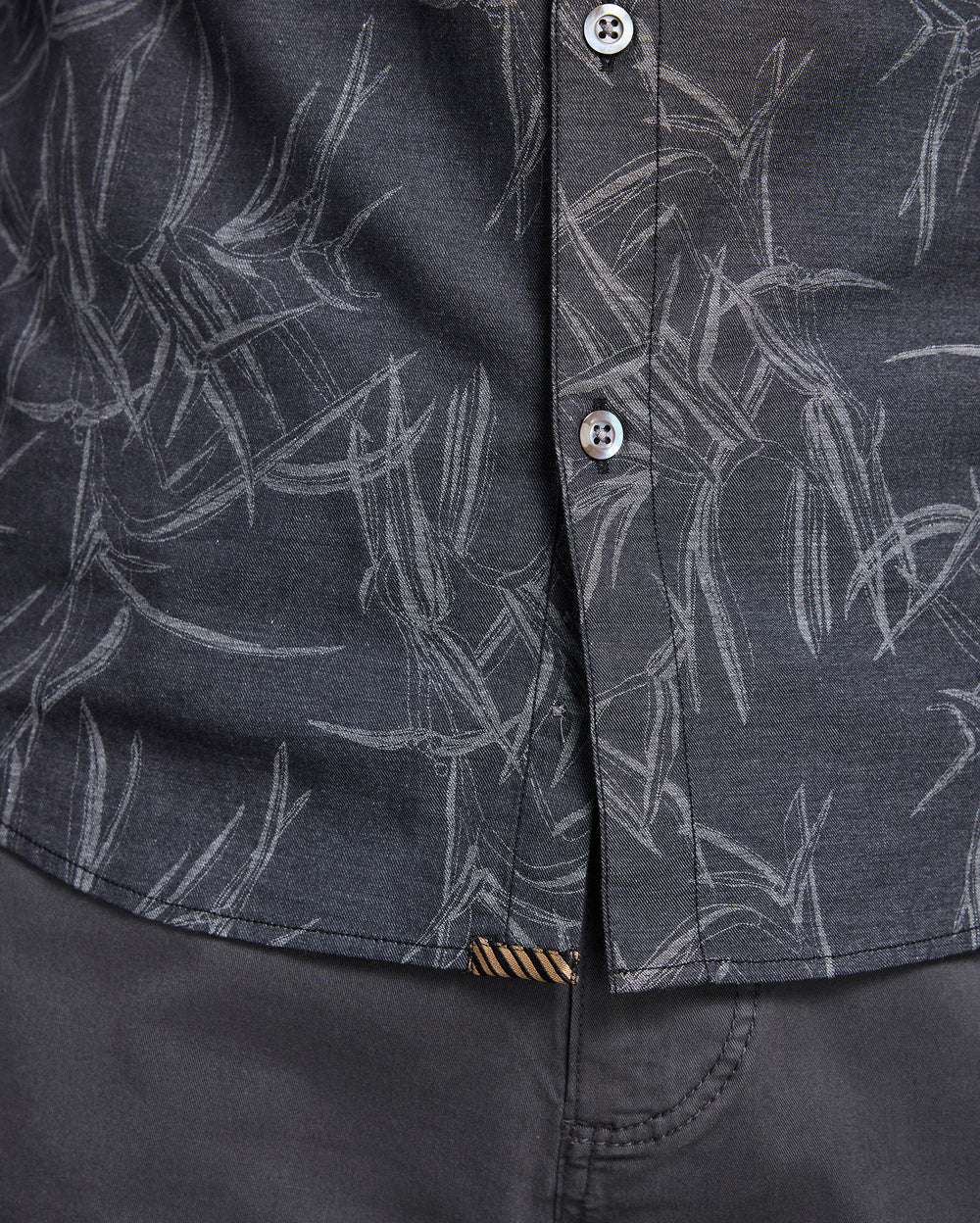 Close-up of a dark gray shirt with white abstract pattern and button details.