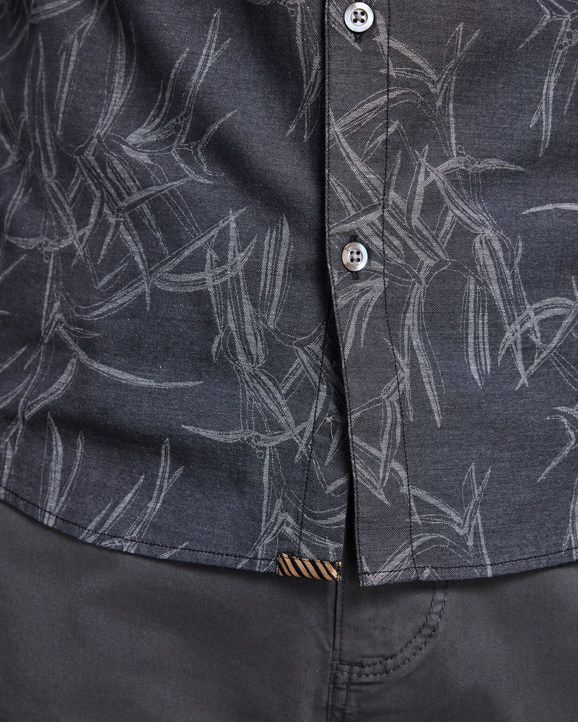Close-up of a dark gray shirt with white abstract pattern and button details.