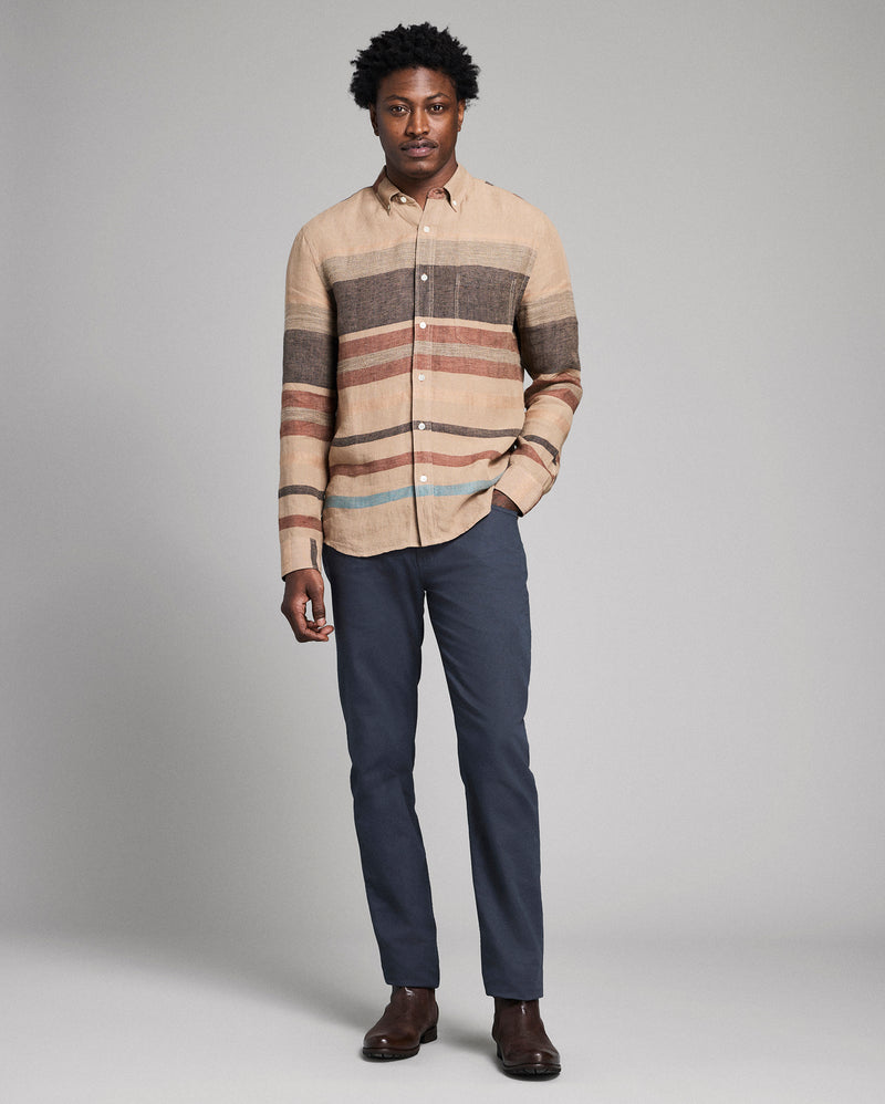 Man wearing a striped shirt and dark pants against a gray background Alternate