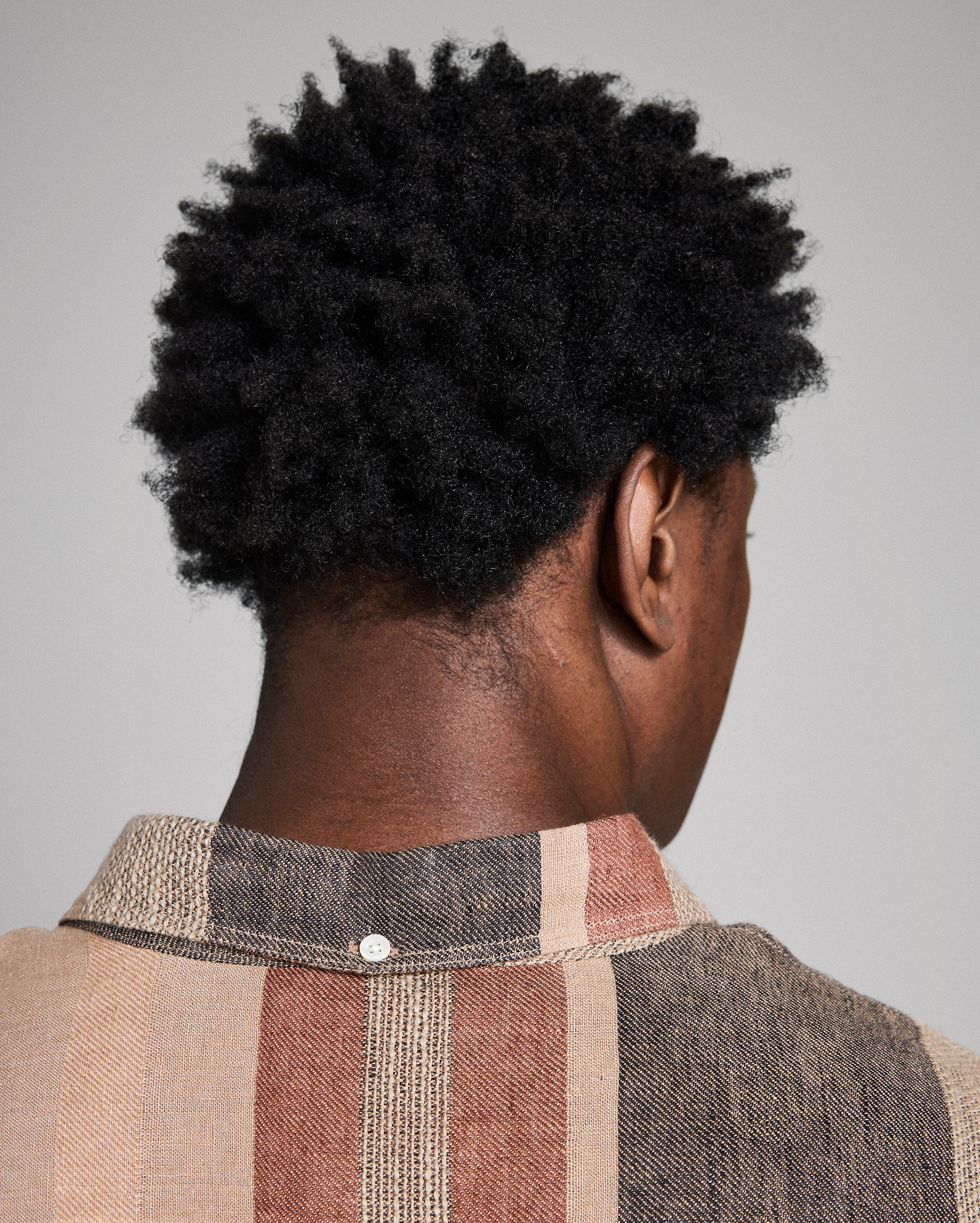 Person wearing a plaid shirt with a neutral background