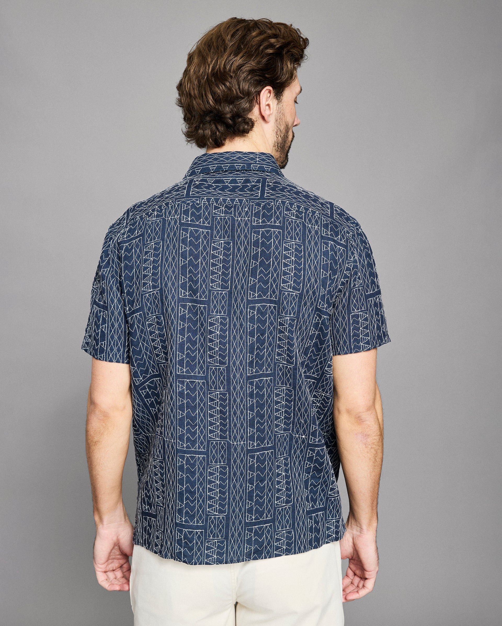 Man wearing a navy patterned shirt against a gray background