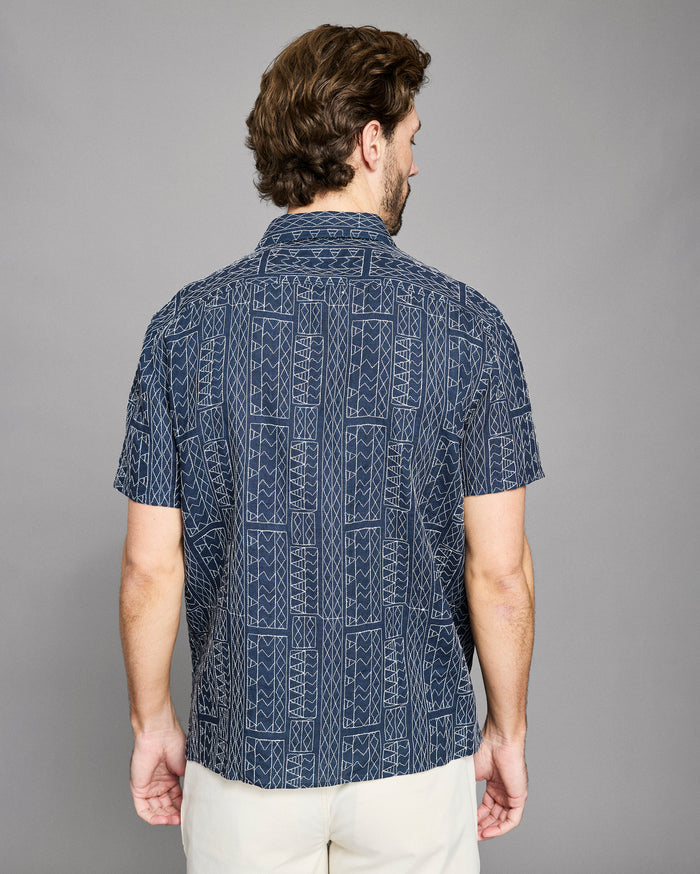 Man wearing a navy patterned shirt against a gray background
