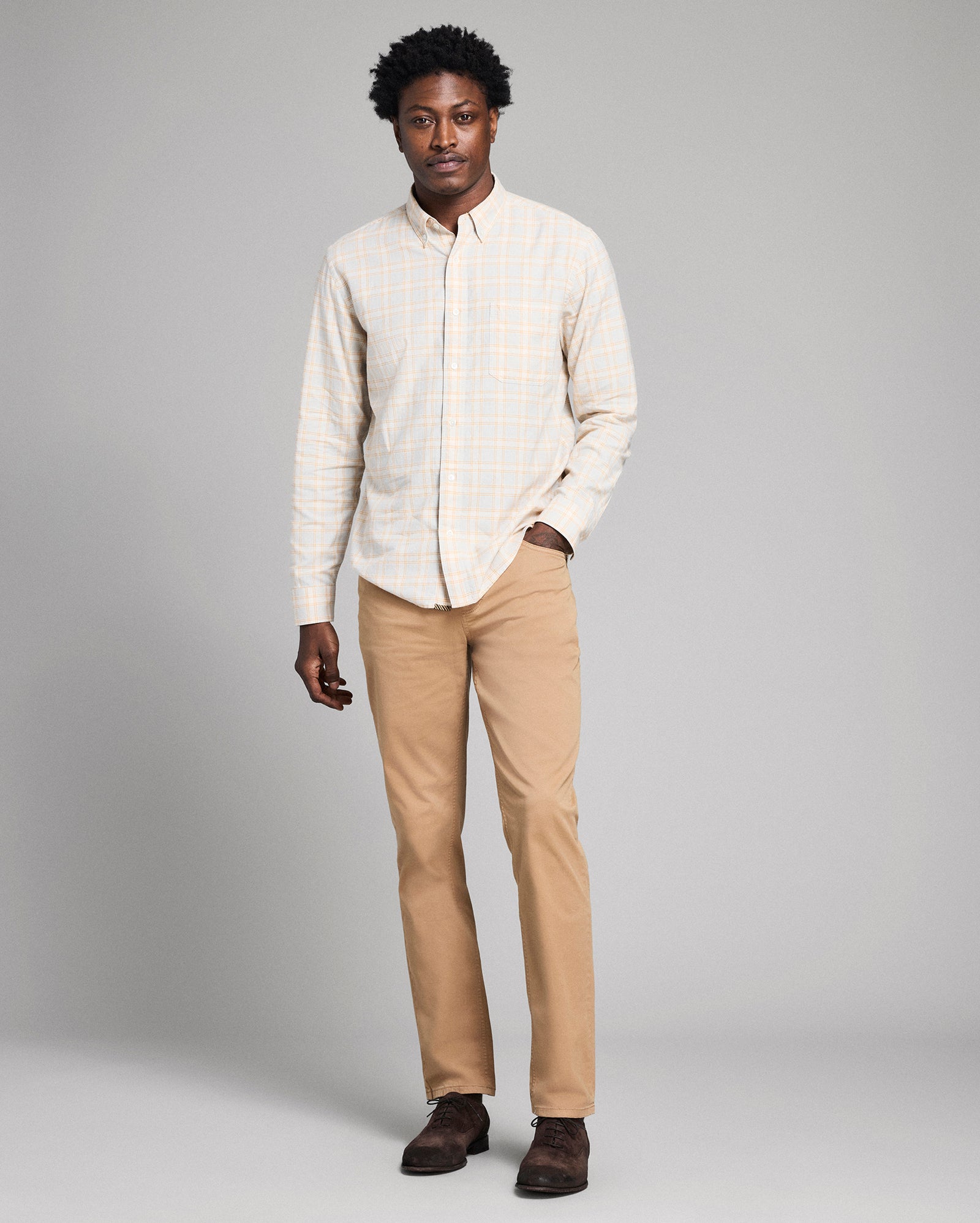 Man wearing a light-colored shirt and beige pants against a gray background